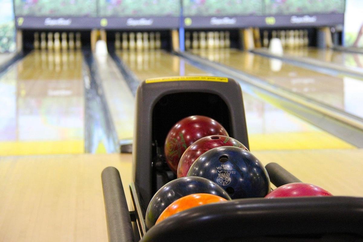 Balle de bowling colorée dans le porte-balles, pistes et quilles visibles Balle de bowling colorée dans le porte-balles, pistes et quilles visibles