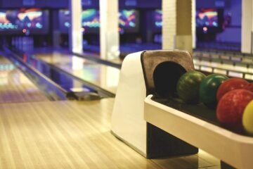 Allée de bowling avec porte-balles contenant des boules vertes, rouges et jaunes