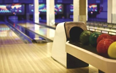 Allée de bowling avec porte-balles contenant des boules vertes, rouges et jaunes