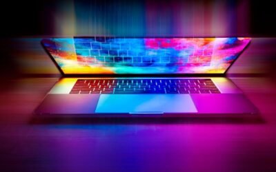 Un ordinateur portable ouvert projette des couleurs vives sur le bureau